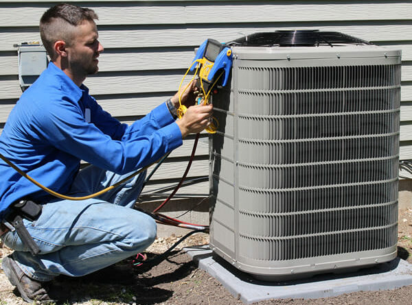 HVAC technician repairing an outdoor air conditioning unit using professional tools, ensuring efficient cooling system performance